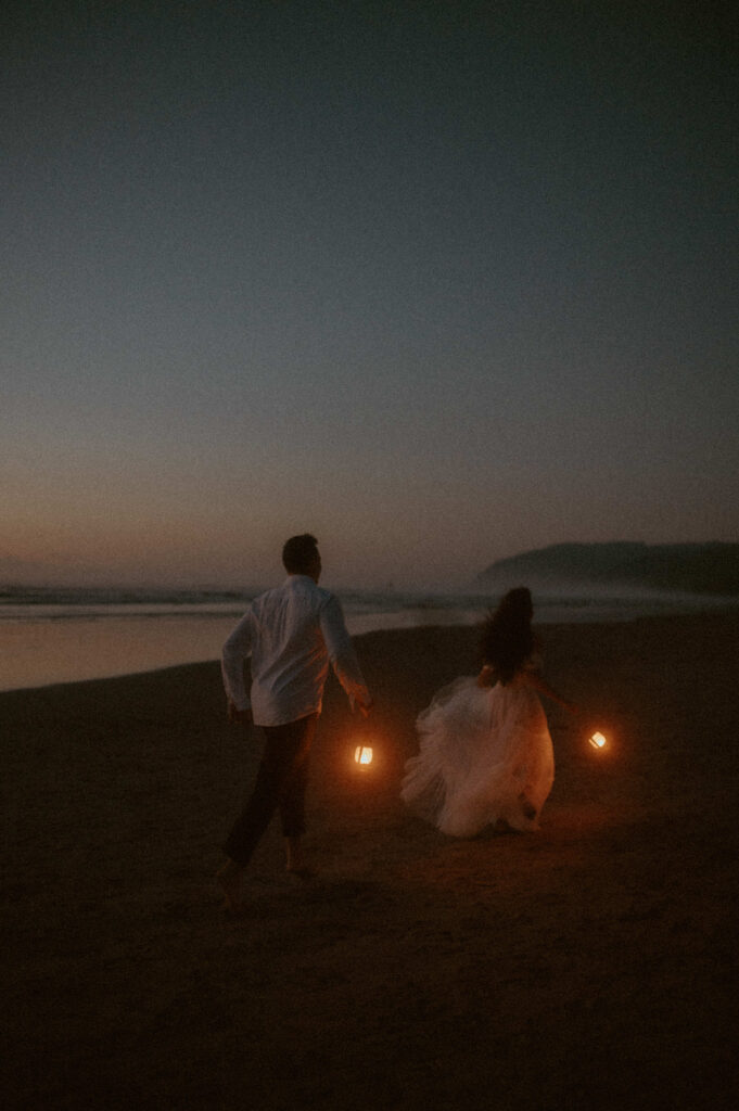couple running with lanterns on the Oregon coast for their elopement at cannon beach