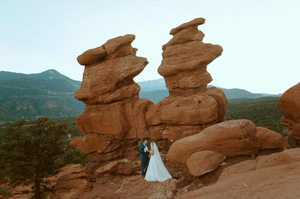 couple eloping at siamese twins in garden of the gods colorado reading their vows intimate elopement at siamese twins rock formation