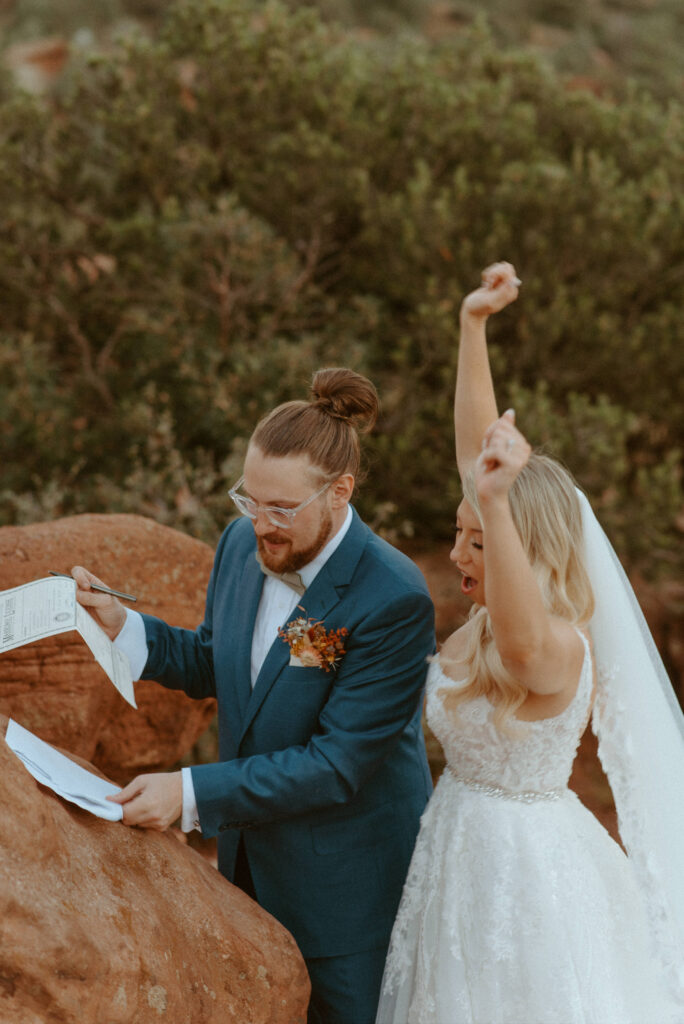 eloping couple celebrating and signing marriage license in garden of the gods in colorado springs